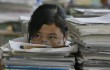 A middle school student sits behind a pile of books and notes in Anxian